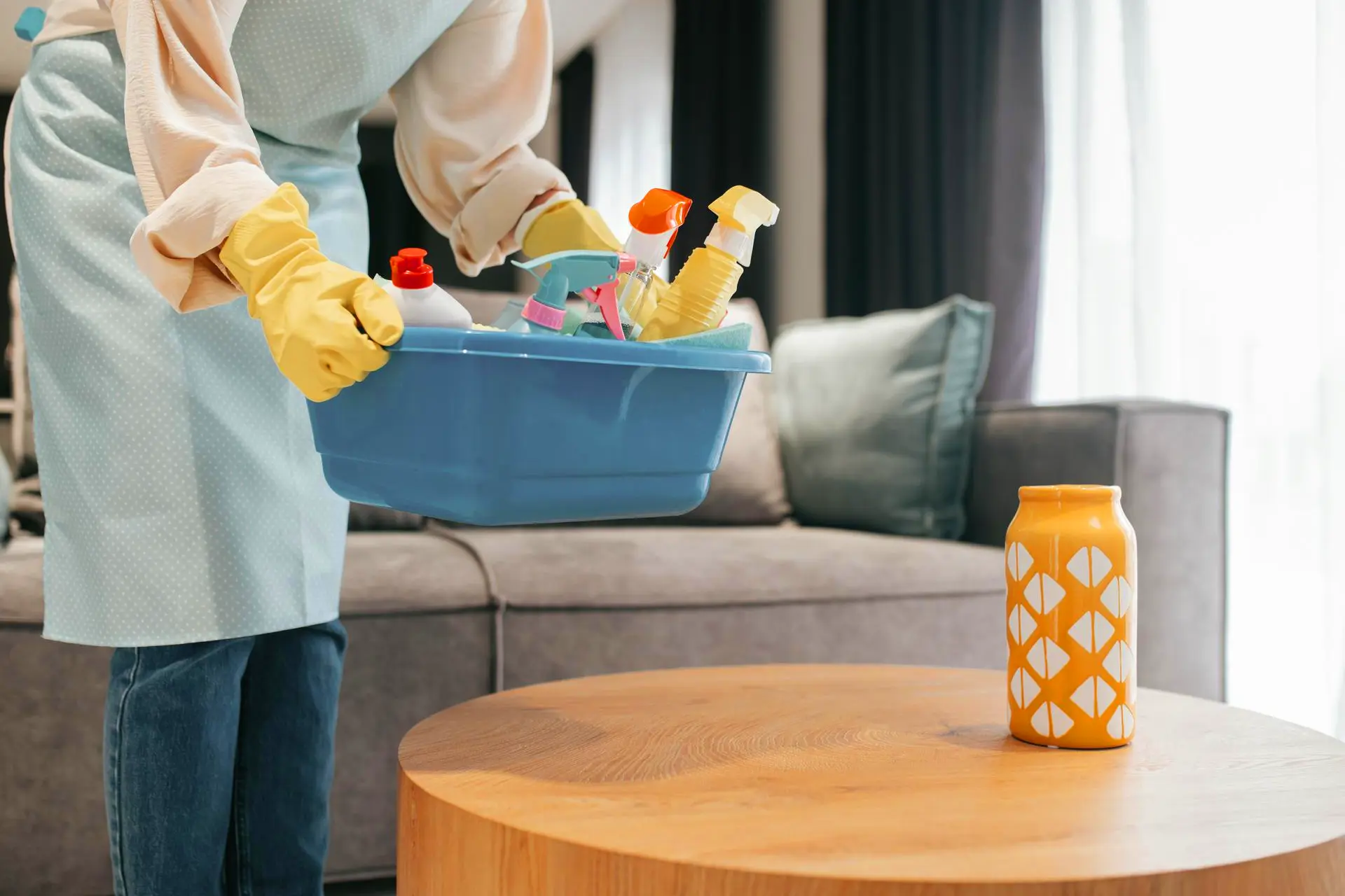 Cleaning person with basket of cleaning products in background.