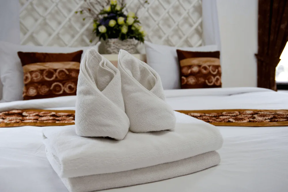 Towels and washcloths, folded in a decorative style on a bed.